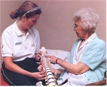 A physiotherapist (left) showing a patient a model of the spine in order to explain her treatment and the cause of the problem presented.