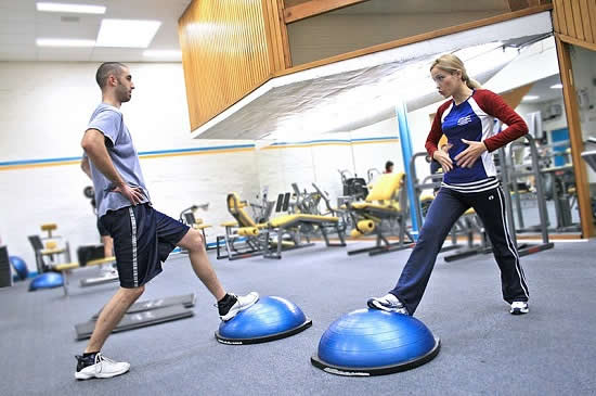 Two_people_in_a_gym_using_BOSU_ball