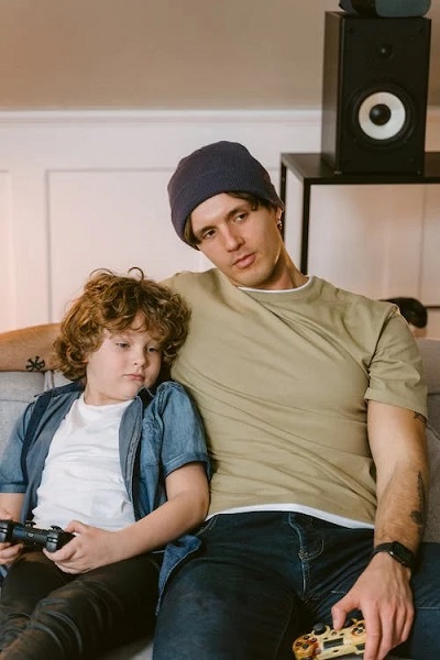 Father and Son Sitting on Sofa with Game Controller